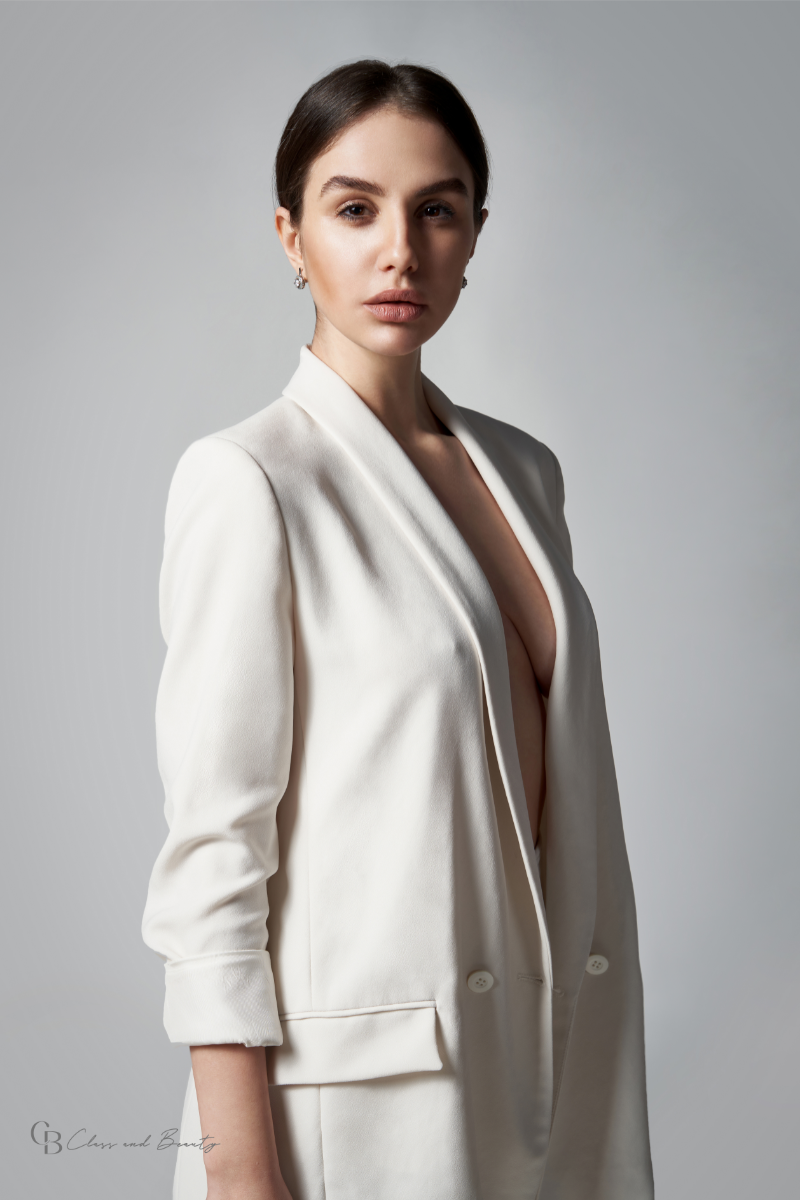 Elegant woman wearing a white blazer, a key piece for a Fall capsule wardrobe, embodying timeless style.