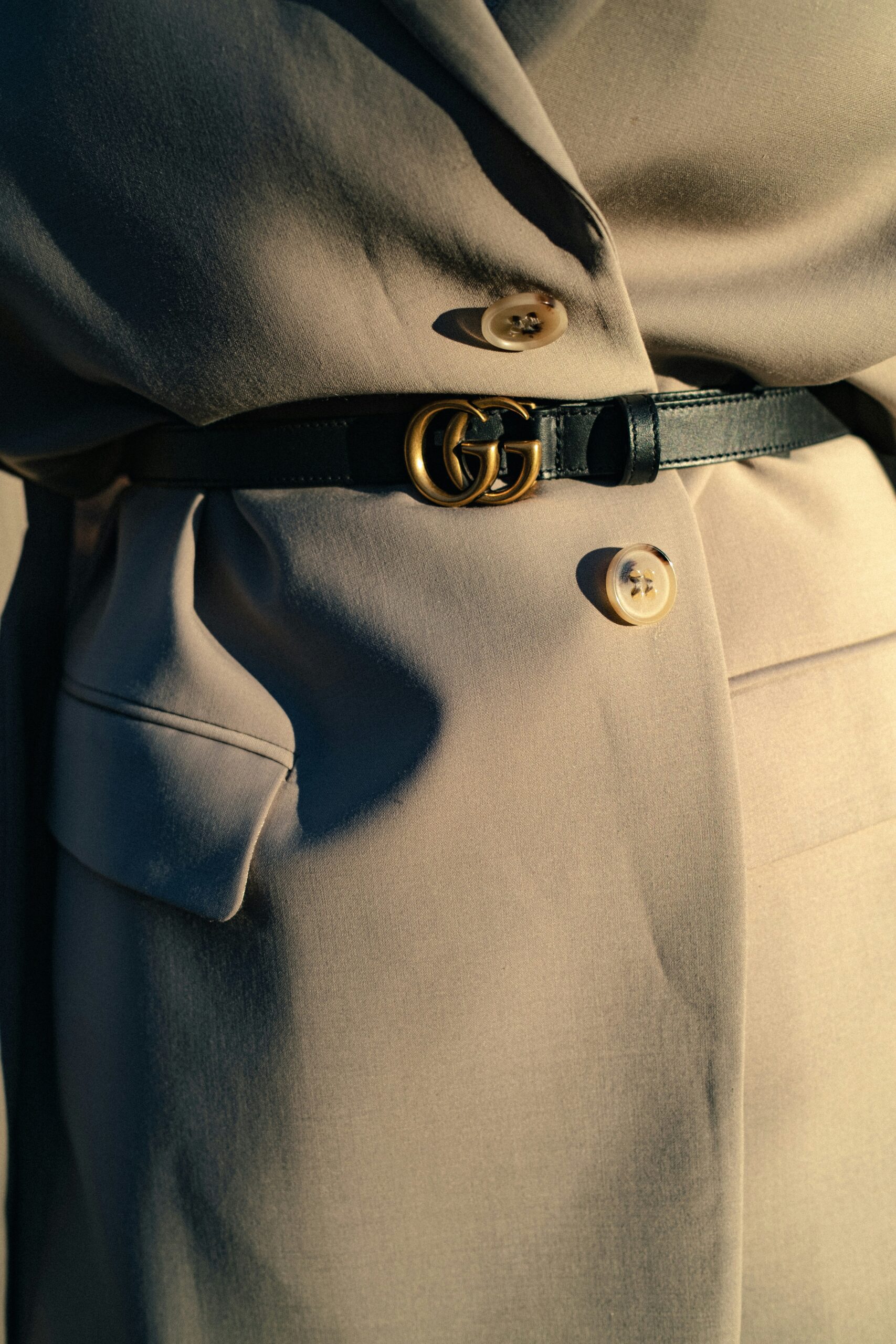 Close-up of a Gucci belt on a sophisticated coat, representing old money aesthetic