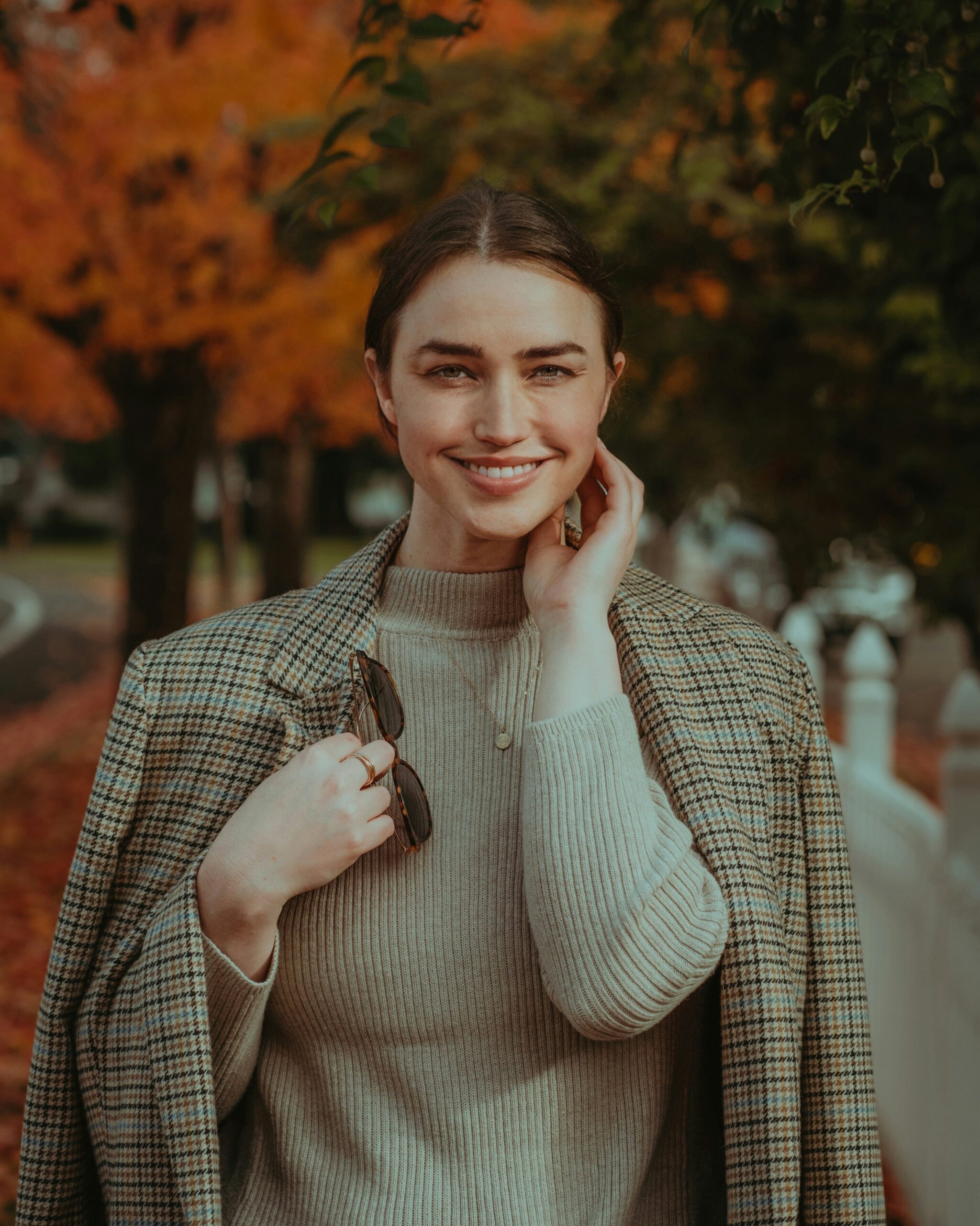 Woman in autumn fashion with a plaid blazer, smiling and embracing old money aesthetic